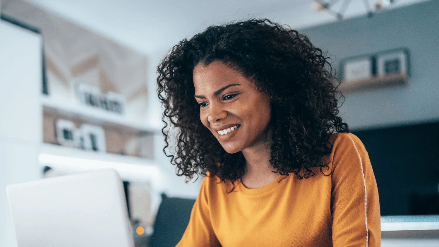 A woman smiling as she reviews a website on her laptop